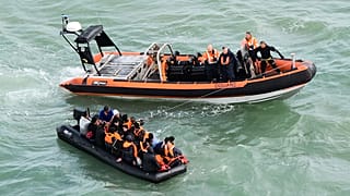 Migrants sitting in an inflatable dinghy rescued by French coast guards while trying to cross the Channel between France and Britain
