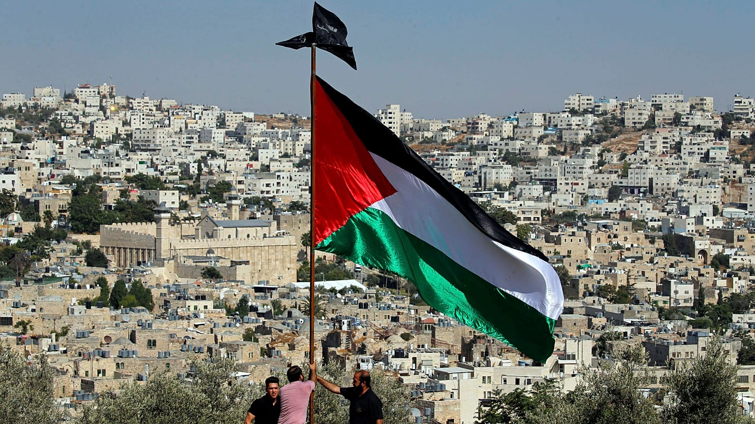 متظاهرون يرفعون العلم الفلسطيني خلال احتجاج على الزيارة المزمعة لرئيس الوزراء الإسرائيلي نتنياهو إلى مدينة الخليل في الضفة الغربية