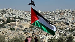 متظاهرون يرفعون العلم الفلسطيني خلال احتجاج على الزيارة المزمعة لرئيس الوزراء الإسرائيلي نتنياهو إلى مدينة الخليل في الضفة الغربية