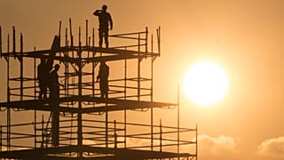 Workers are seen in silhouette, along with the Eiffel Tower, as they construct scaffolding on the Place de la Concorde as the sun sets on an autumn day in Paris, France