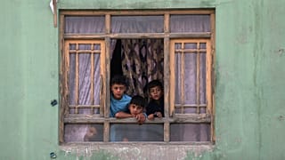 Afghan children look out from a broken window at the site of a blast in Kabul