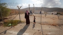فلسطينيون يقفون إلى جانب السياج في وادي الأردن في الضفة الغربية المحتلة