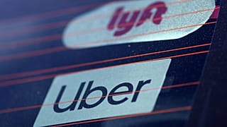 Uber and Lyft signs are seen on a car in Redondo Beach