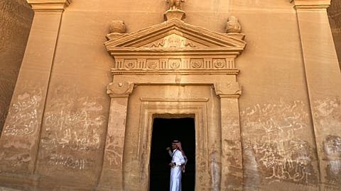 A tour guide stands inside a tomb at Madain Saleh