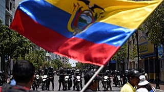 Demonstrators wave the national flag while facing riot police during protests against Ecuador's President Lenin Moreno's austerity measures