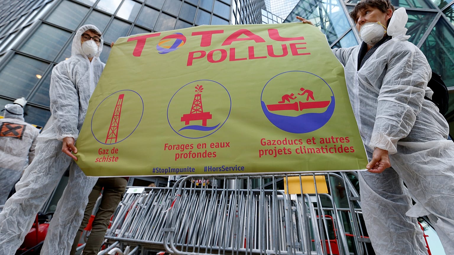 El movimiento antiglobalización Attac sostiene una pancarta frente al edificio Total mientras protestan en La Defense, cerca de París, Francia, el 12 de octubre de 2019.