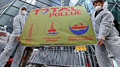 El movimiento antiglobalización Attac sostiene una pancarta frente al edificio Total mientras protestan en La Defense, cerca de París, Francia, el 12 de octubre de 2019.