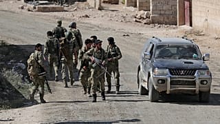 Turkey-backed Syrian rebel fighters walk together near the border town of Tel Abyad, Syria, October 12, 2019.