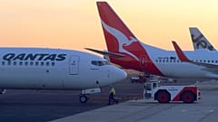 FILE PHOTO: Workers are seen near Qantas Airways, Australia's national carrier, Boeing 737-800 aircraft on the tarmac at Adelaide Airport