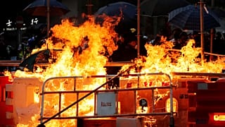 Protesters set fire on a barricade as policemen advance toward them during an anti-government protest protest in Hong Kong, China, October 20, 2019