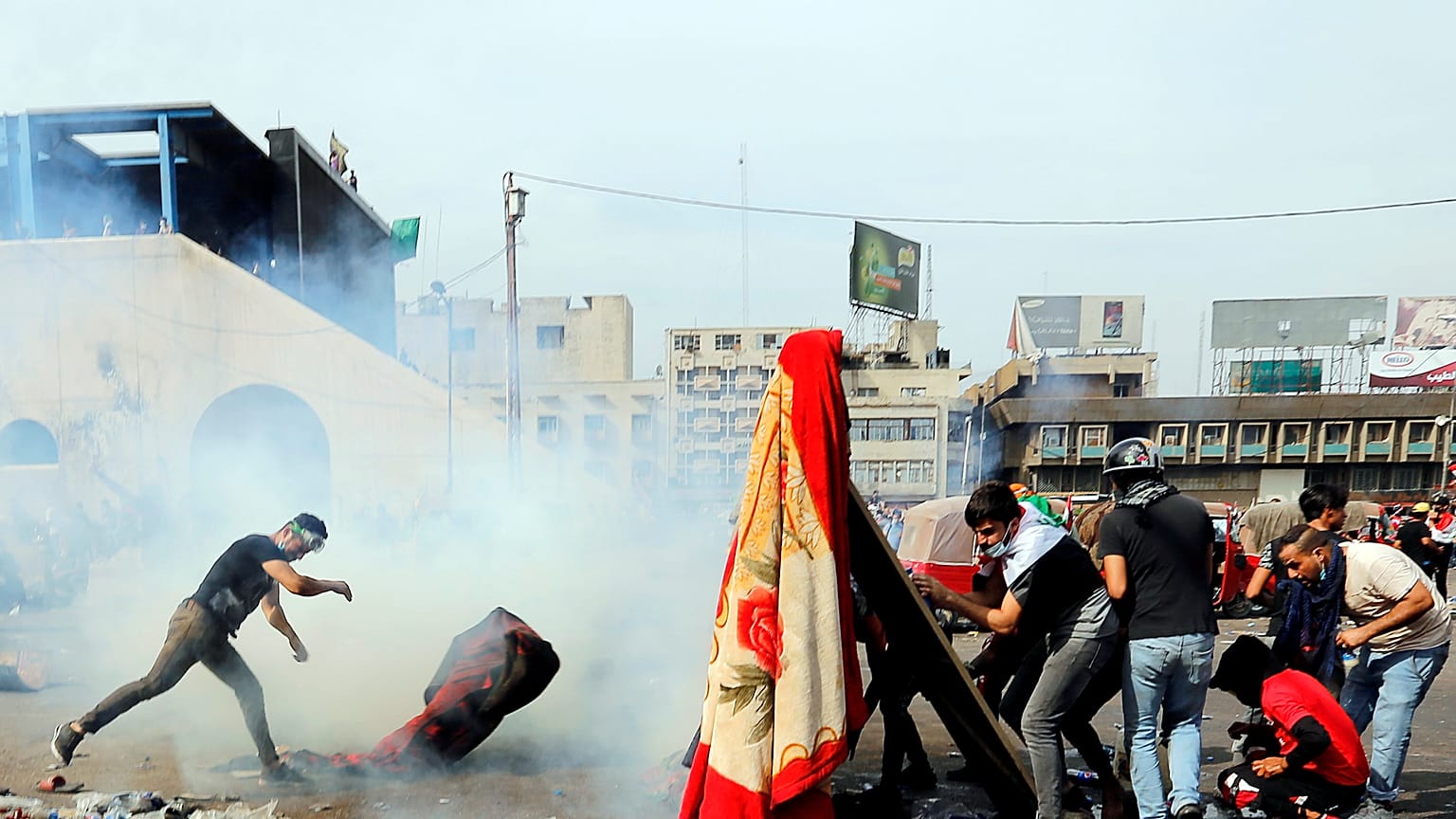 Protesters in Baghdad attempt to throw tear gas canisters back at security services 