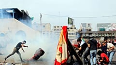 Protesters in Baghdad attempt to throw tear gas canisters back at security services 