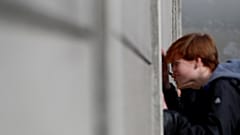 Visitors peers through segments of Wall at the Berlin Wall memorial on Bernauer Strasse in Berlin