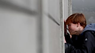 Visitors peers through segments of Wall at the Berlin Wall memorial on Bernauer Strasse in Berlin