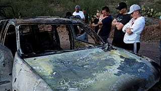 Parenti delle vittime osservano sgomenti uno delle auto carbonizzate.