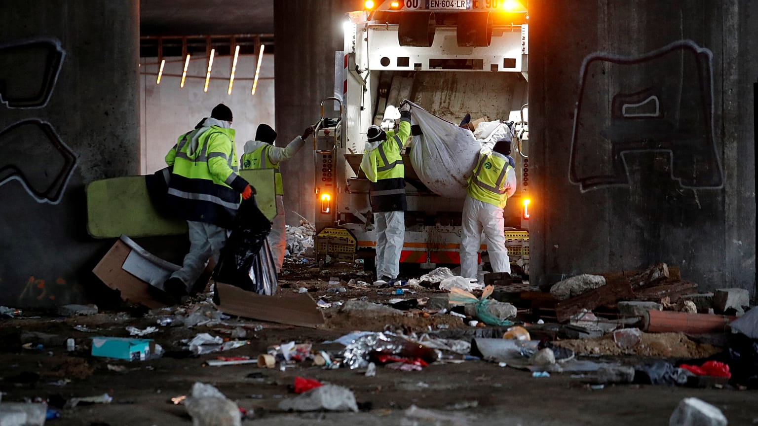 Workers clean the site after a migrant makeshift camp was evacuated under the Porte de la Villette ring bridge in Paris, France.