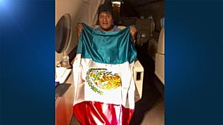 Former Bolivian President Evo Morales holds a Mexican flag onboard a Mexican government's aircraft in an unidentified location November 11, 2019