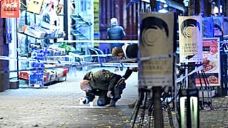 A police officer marks evidence at the crime scene where a 15-year-old was fatally hit and another severely wounded when attackers opened fire on a pizzeria