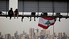متظاهرون يجلسون على لافتة على طريق مظاهرة تسد الطريق السريع خلال الاحتجاجات المستمرة المناهضة للحكومة في الحازمية، لبنان 13 نوفمبر/ تشرين الثاني 2019