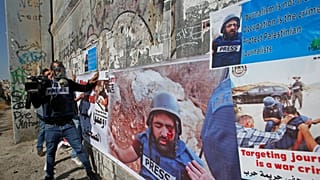 صحفيون فلسطينيون يضعون ملصقات تظهر زميلهم معاذ العمارنة الذي أصيب بعيار ناري في عينه تضامنا معه في بيت لحم في الضفة الغربية