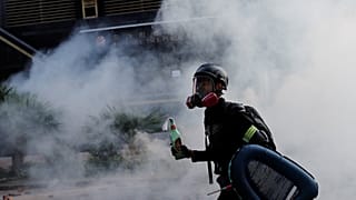 Ein Demonstrant schützt sich mit Gasmaske vor dem Rauch