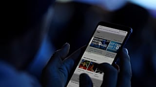 FILE PHOTO: November 13, 2019 A spectator looks at his mobile phone during Tennis - ATP Finals 