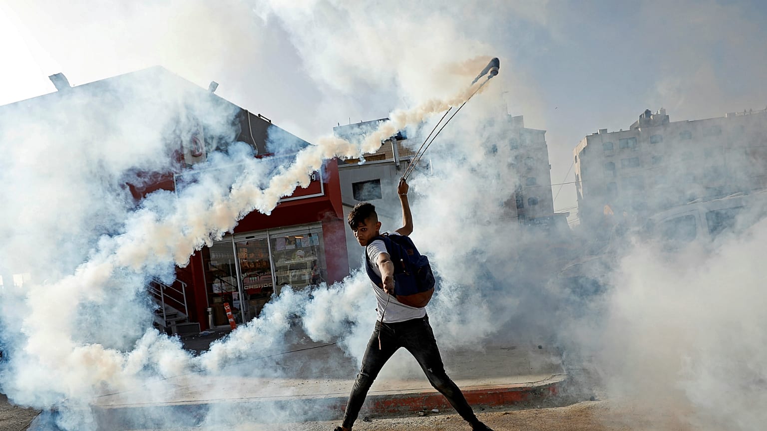 متظاهر فلسطيني يعيد قنبلة الغاز بالقرب من مستوطنة بيت إيل، الضفة الغربية- أرشيف رويترز