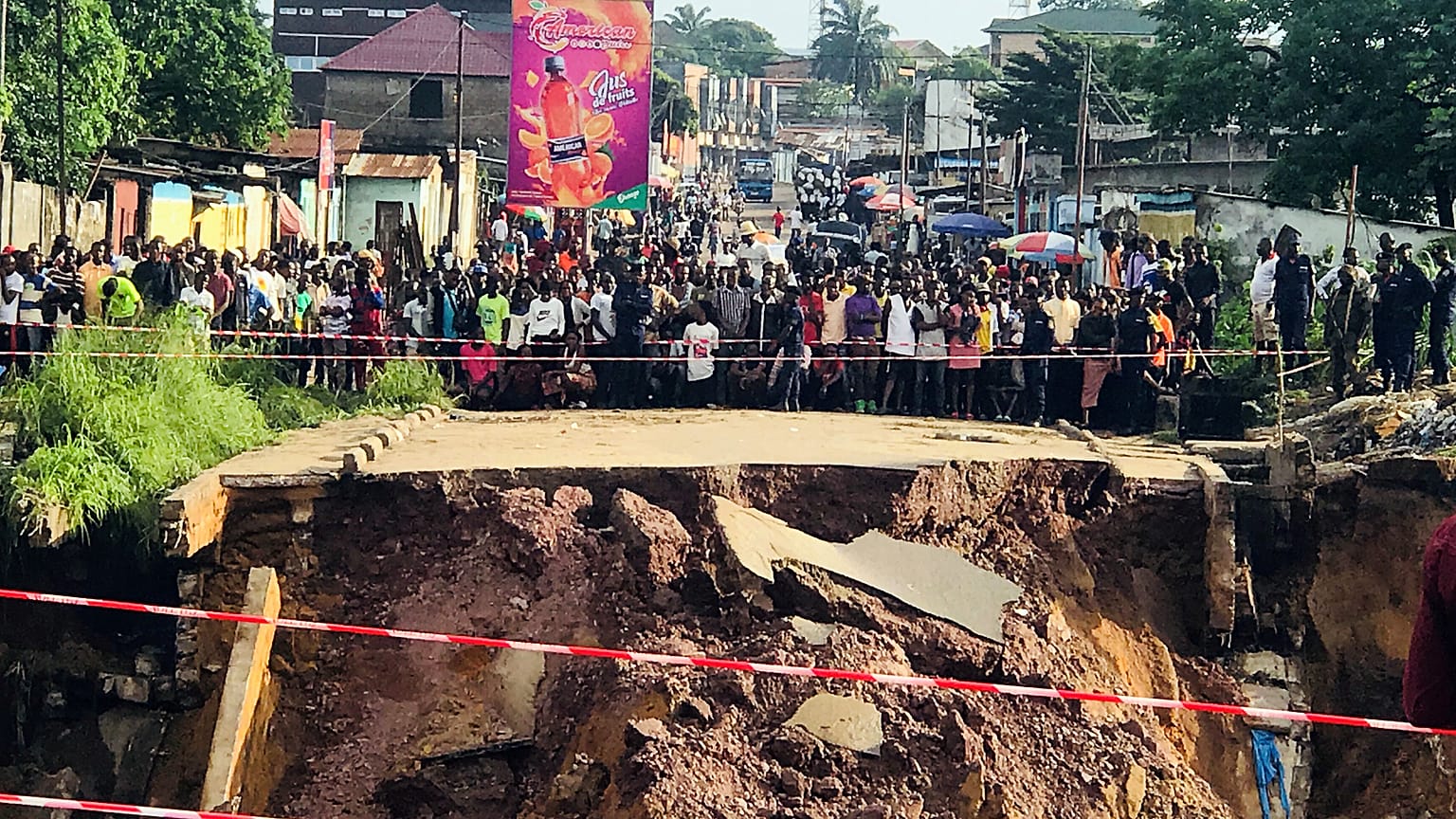 Des habitants de Kinshasa, devant une route coupée en deux.