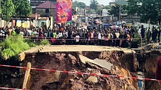 Des habitants de Kinshasa, devant une route coupée en deux.