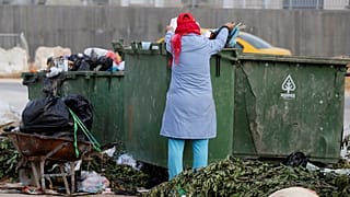 امرأة تجمع قارورات البلاستيك من صندوق للقمامة في تونس