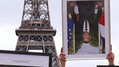 French climate activists hold stolen Macron portraits at protest