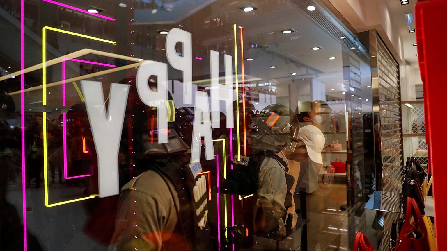Police officers are seen through a shop window as they detain a demonstrator, during an anti-government protest inside a mall, in Hong Kong, China December 15, 2019. 