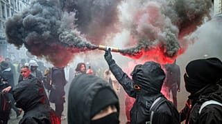 A protester holds up a flare during a demonstration in Lyon, central France, Tuesday, Dec. 17, 2019.