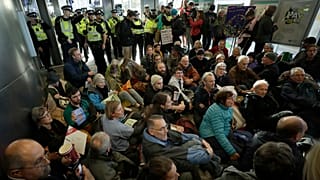 Police Officers stand guard as Extinction Rebellion demonstrators peacefully block an entrance to City Airport in London, Thursday, Oct. 10, 2019.