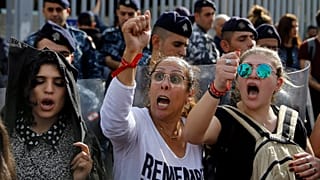 Protesters chant slogans against the Lebanese political class as riot police stand guard in front of Finance Ministry building in Beirut, Lebanon, Nov. 29, 2019