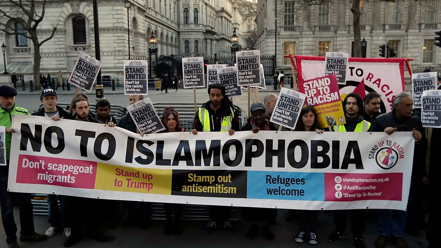 People hold up a banner during a 'Unity Vigil' against racism and Islamophobia in reaction to Wednesday's attack, backdropped by the gates of Downing Street in London