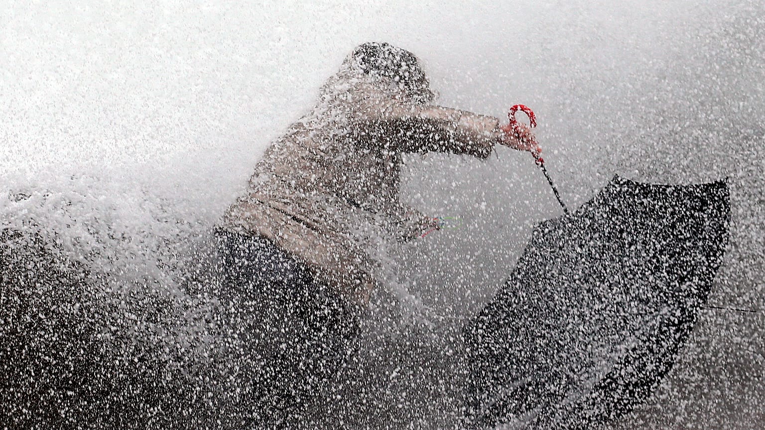 A woman tries to keep her balance as waves hit the seawall in Biarritz, southwestern France, Sunday, Dec.22, 2019