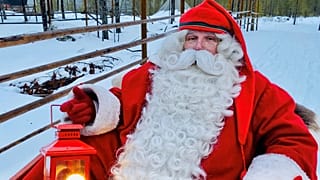 A man dressed as Santa Claus poses for a picture near Santa Claus Office located on the Arctic Circle near Rovaniemi