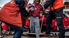 Einem Jungen wird von Helfern im spanischen Algeciras an Land geholfen.
