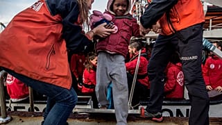 Einem Jungen wird von Helfern im spanischen Algeciras an Land geholfen.