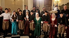 Το πρωθυπουργικό ζεύγος και η κόρη τους, ακούν τα χριστουγεννιάτικα κάλαντα από  τους Σύλλογους Ασιγωνιωτών «Παύλος Γύπαρης» και Ένωση Κρητών «Άγιος Ανδρέας Κρήτης»