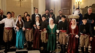 Το πρωθυπουργικό ζεύγος και η κόρη τους, ακούν τα χριστουγεννιάτικα κάλαντα από  τους Σύλλογους Ασιγωνιωτών «Παύλος Γύπαρης» και Ένωση Κρητών «Άγιος Ανδρέας Κρήτης»