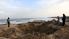 فلسطينيون يتفقدون موقع ضربة جوية إسرائيلية في جنوب قطاع غزة