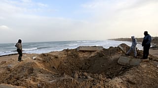 فلسطينيون يتفقدون موقع ضربة جوية إسرائيلية في جنوب قطاع غزة