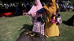 Women sprinkle flowers on a stone marking the mass grave for the victims of 2004 tsunami, during a commemorative service in Banda Aceh, Indonesia, Dec. 26, 2018. 