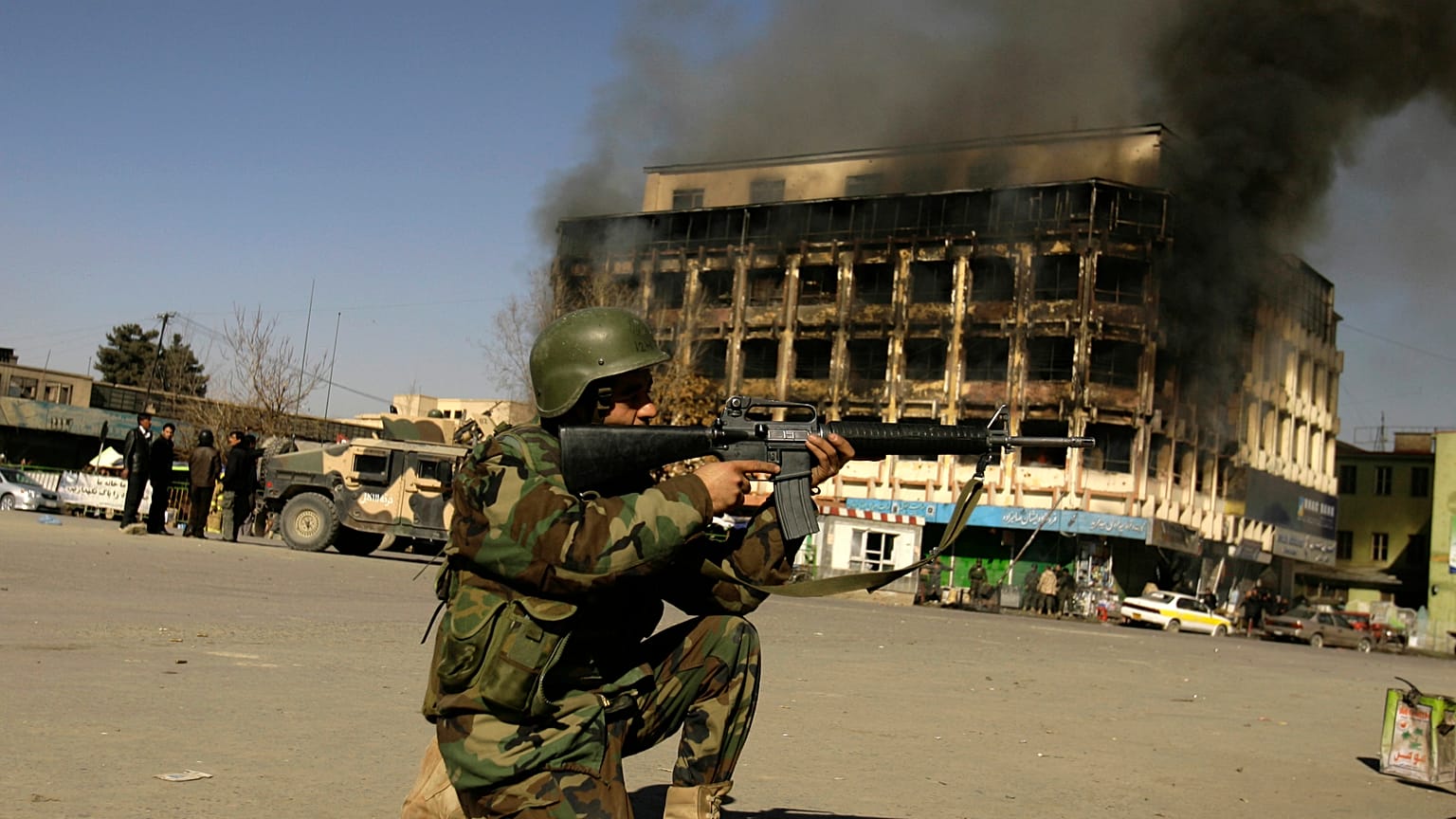 An Afghan police officer aims his weapon at the scene of attack in central Kabul, Afghanistan, Monday, Jan. 18, 2010 (AP Photo/Ahmad Massoud)