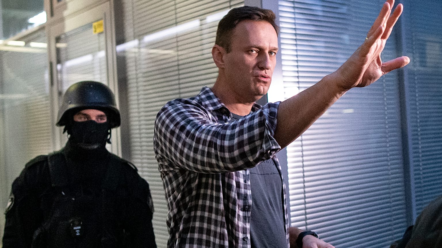 Alexei Navalny gestures while speaking to the media as a security officer guards an entrance of the Foundation for Fighting Corruption office in Moscow, Russia,  Dec.26