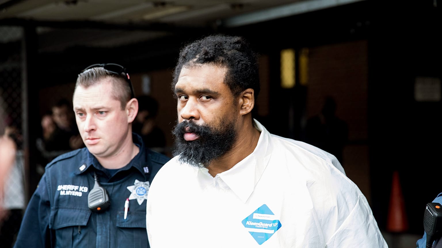 Police officers escort Grafton Thomas to a police vehicle.