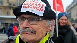 A demonstrators wears a sticker on his hat that reads, "no to Macron's pension reform during a protest in Paris, Saturday, Dec. 28, 2019. 