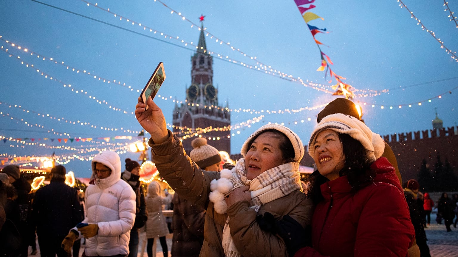 Tourists take a selfie in Red Square decorated for New Year celebrations, with the the Kremlin's Spasskaya Tower in the background, in Moscow, Russia.